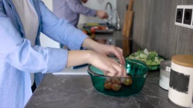 kesme domates ve salatalık üzerinde beyaz plastik tahta kesme ve bir salata kaseye koyarak bir kadındır