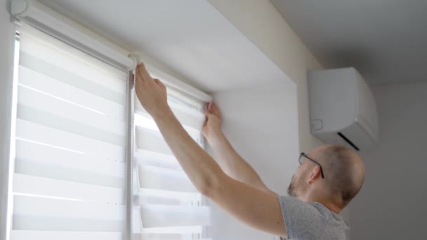 Yetişkin adam gündüz vakti bir pencere çerçevesi bir oturma odasında bir çubuk güneşlikler için yükleme ve perdeleri sabitleme — Stok video