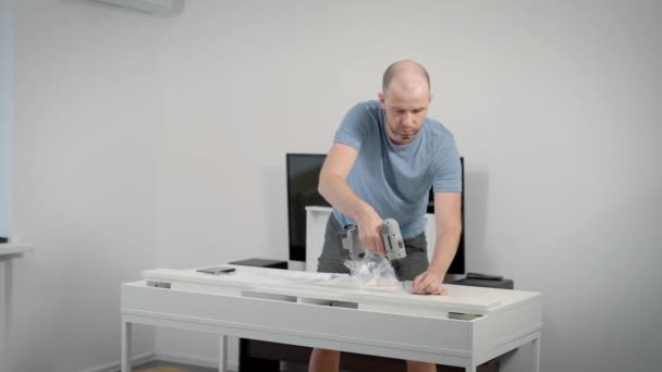 Adult man finishing assembling his work table in house. — Stock Video