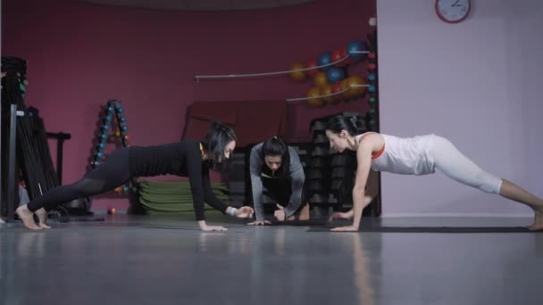 Drie spotswomen zijn doen verschillende oefeningen voor abs in een fitness-studio. — Stockvideo