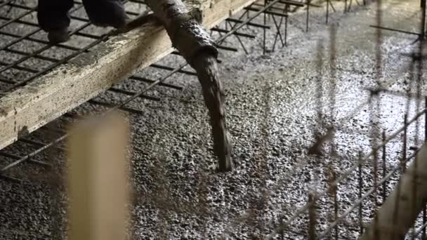 A close shot at the rubber hose, through which cement enters to fill the floor on an industrial site, there is a foreman next to it — Stock Video