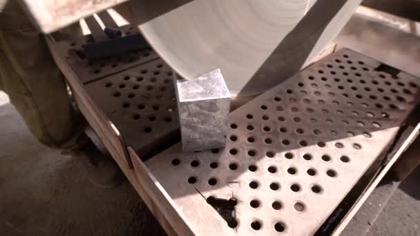 Eine Nahaufnahme auf einer Säge mit Diamantbeschichtung, die sich dreht und ein Stück Stein in zwei Hälften schneidet, das Material steht auf einem Ständer — Stockvideo