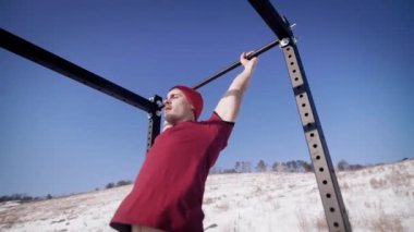 Bir sportif ve güçlü adam bir bar salıncaklar, basın kaslarını güçlendirmek için bir adam onun bacaklarını kaldırdı