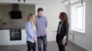 Mutfakta bir genç evli çift bir daire, bir erkek ve bir kadın satın alma olasılığı hakkında bir emlakçı ile iletişim kurar.