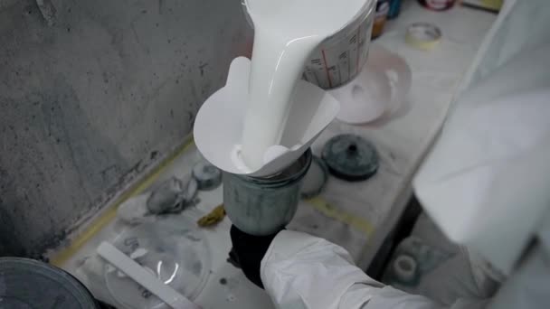 Крупним планом знімок механіки рук, чоловік зайнятий заповненням бочки атомайзера, він вливає в білу фарбу — стокове відео