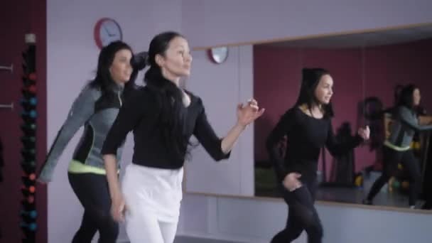 Jonge vrouwen doen actieve oefeningen in de fitnessclub, de dames lopen rond op de plek om de lichaamsspieren brengen Toon en afvallen — Stockvideo