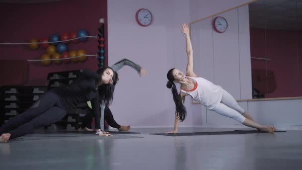 Junge Frauen stehen in der Bar auf Yogamatten, ihr Körper ist angespannt, die Damen wollen abnehmen und die Muskeln für die Sommersaison straffen — Stockvideo