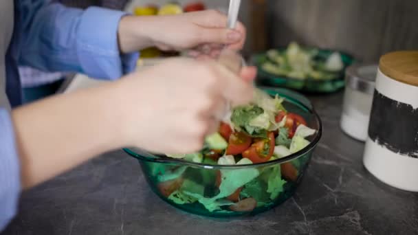 Primer plano de una mujer mezclando verduras frescas verdes en un recipiente de vidrio en un mostrador de cocina . — Vídeos de Stock