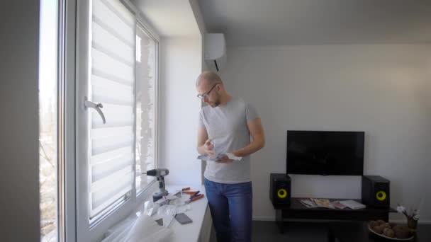 Adult handyman reading an instruction by the window indoor. — Stock Video