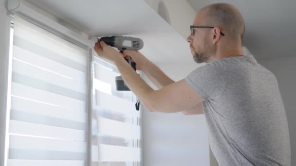 Klusjesman met behulp van boor te installeren mechanisme voor nieuwe blinds. — Stockvideo