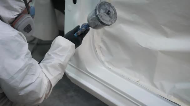 Close up tiro de homem vestindo uniforme protetor pintura saias laterais de um carro em uma garagem . — Vídeo de Stock