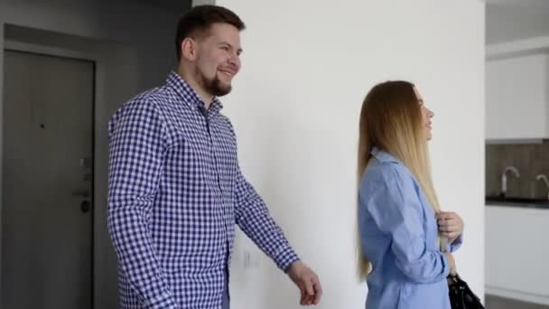 Vista trasera del hombre y la mujer de pie en el apartamento mientras lo mira . — Vídeo de stock