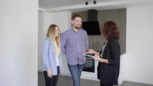 Hombre y mujer interactuando con el agente inmobiliario mientras mira el apartamento en alquiler o comprar — Vídeo de stock