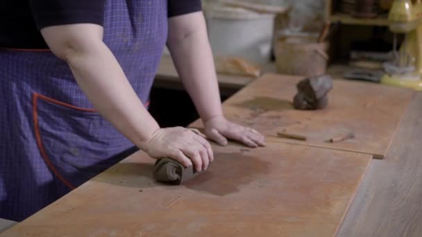 Крупним планом знімок жіночих рук, майстер робить шматок глини м'якшим і плоским у своїй майстерні — стокове відео