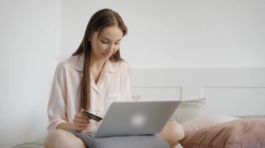 Kız internette Önden Görünüm sitedeki kredi kartını veri yerleştirme yatakta, evinde oturan online satın alıyor