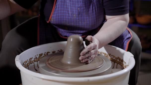 Meester van aardewerk is uitrekken en kneden stukje klei draaien op een platform van pottenbakkers elektrisch aangedreven wiel, in een winkel — Stockvideo