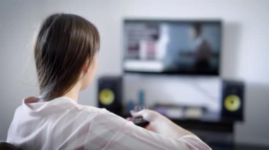 Koltukta oturan kapalı tv izlerken bir esmer kadının arkadan atış yukarıya kapatmak.