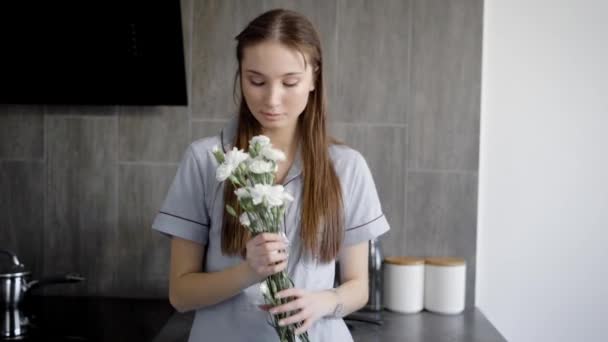 Portræt af dejlig brunette kvinde holder blomster indendørs . – Stock-video