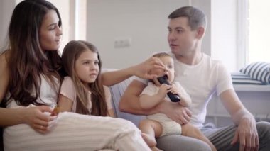 Mutlu Avrupa aile tv önünde kanepede oturuyor.