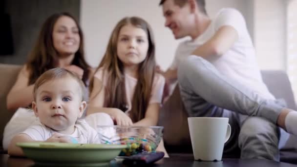 Vue de face d'une famille de quatre personnes passant du temps devant la télévision intérieure . — Video