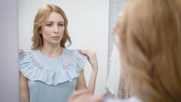 Primer plano de una mujer encantadora probándose un nuevo vestido azul . — Vídeo de stock