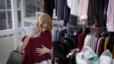 genç bir kadın kıyafetleri şık bir butik seçer, bir lady askı tartmak kazak inceliyor