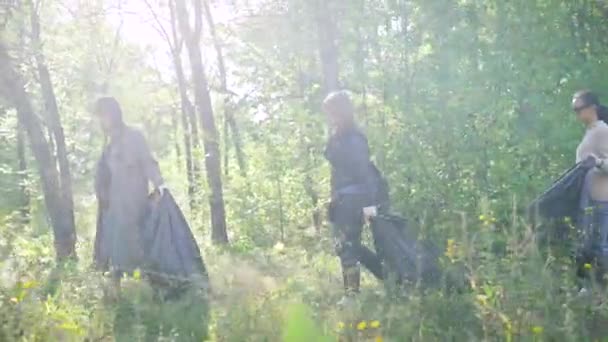 Le donne trasportano sacchetti di plastica con rifiuti che camminano nella foresta, i bambini vanno in bicicletta, si muovono dietro — Video Stock