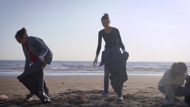 Fiatal nők csoportja takarít strand műanyag szemét nyáron reggel, takarítás területén pihenni — Stock videók