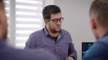 Yaratıcı iş. Ofisteki toplantıda bir adamın portresi. Tarz sahibi genç adam iş arkadaşlarıyla konuşuyor..