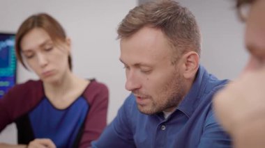 Yaratıcı iş. Ofisteki toplantıda bir adamın portresi. Tarz sahibi genç adam iş arkadaşlarıyla konuşuyor..