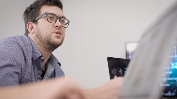 À la réunion. Un homme se sent avec des collègues dans une salle de réunion. Un programmeur à lunettes discute du développement 
