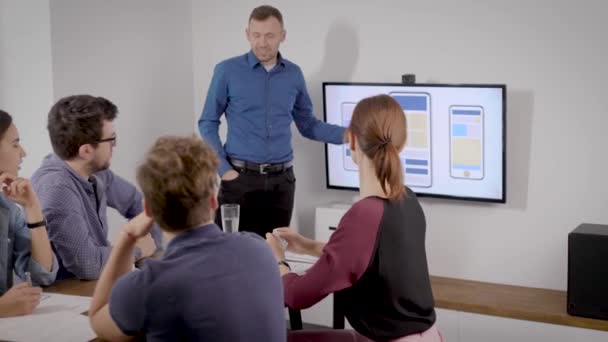 Rendez-vous au bureau. Un homme fait une présentation à sa manière pour ses collègues. Diapositives d'affaires sont affichées à la télévision .