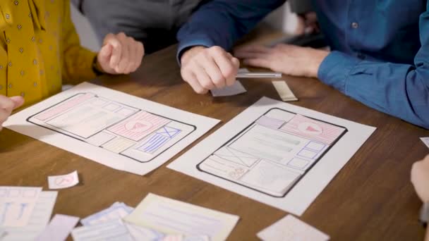 Brainstormen. In het frame zitten de handen van ontwerpers en lay-outs van de mobiele applicatie. Ontwikkelaars werken in de ontwerpfase aan functionaliteit. — Stockvideo