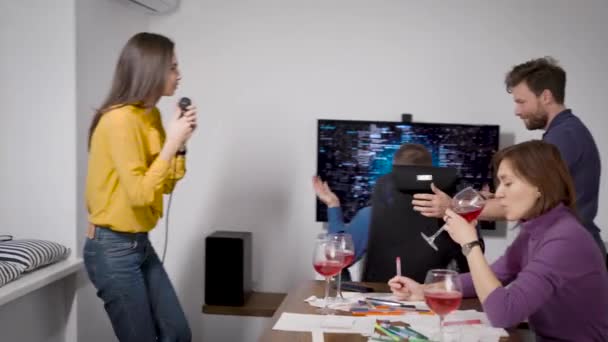 Tvůrčí obchodní přátelé. Večírek v kanceláři s karaoke. Dívka zpívá do mikrofonu a tancuje. — Stock video