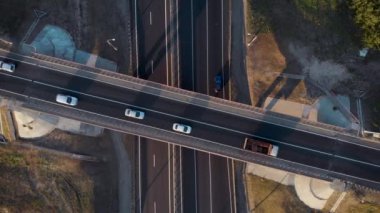 havadan görünüm. Şehirlerarası otoyolda kavşak. Arabalar ve kamyonlar farklı yönlere seyahat ederler. Her yönde iki çizgi.