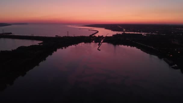 Vista aérea. Puesta de sol sobre el canal de agua. En el marco, una presa o puente es fuerte. La presa cubre la piscina de un enorme río . — Vídeo de stock