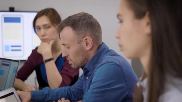 Vrouwen en mannen discussiëren in kantoor over de ontwikkeling van mobiele apps tijdens zakelijke bijeenkomst — Stockvideo