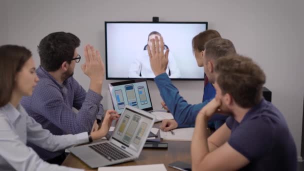 Irodai szakemberek csapata szavaznak az üzleti találkozóról a főnökkel videohívással a konferenciateremben — Stock videók