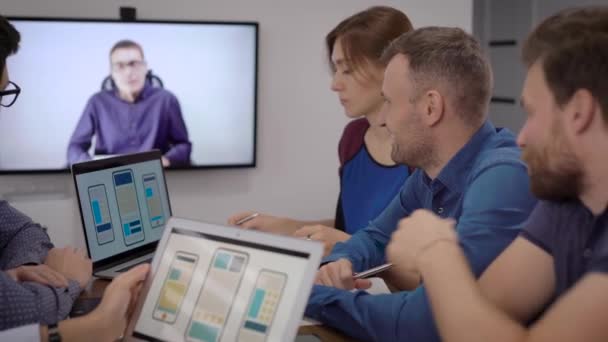 développeurs de logiciels pour téléphones mobiles sont à l'écoute spécialiste en chef par vidéoconférence dans la salle de conférence 
