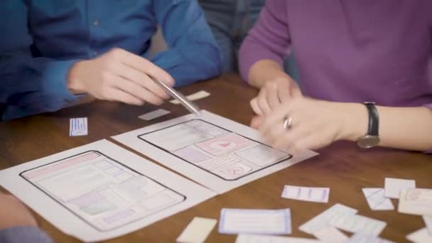 Engenheiros estão desenvolvendo aplicativos para smartphones, colocando papéis na mesa no escritório, close-up de mãos — Vídeo de Stock