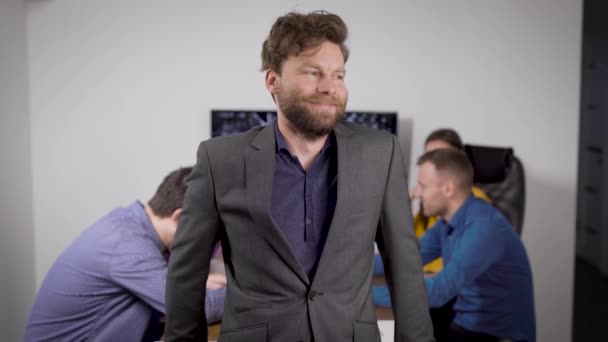 Joyeux PDG sourit debout dans la salle de bureau en face de la caméra, les employés se réunissent derrière lui — Video