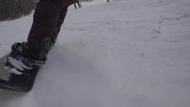 View from behind. The snowboarder drives fast on a snowy slope. Extreme sports. — ストック動画