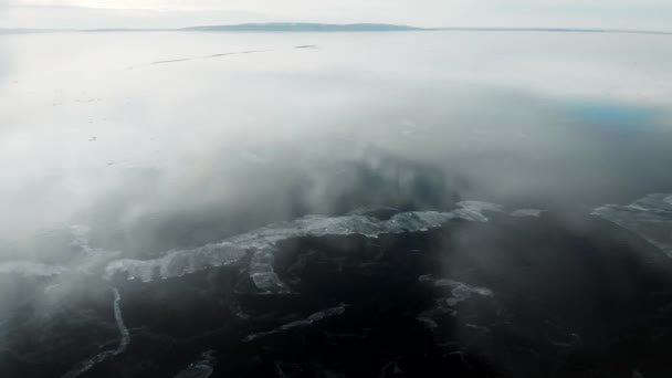 To widok z lotu ptaka. Szybki ruch kamery nad świeżo zamarzniętą rzeką. Lód jest gładki, z pęknięciami i powietrzem. Chmury odbijają się na powierzchni. — Wideo stockowe