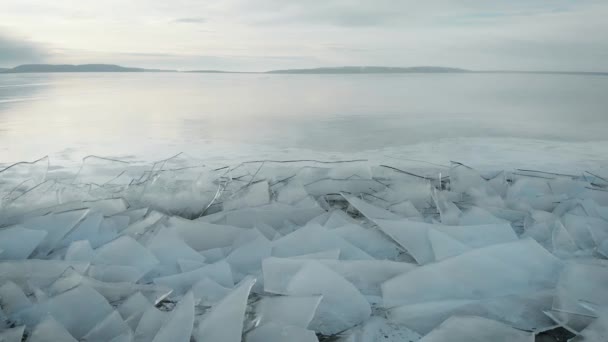 Die nördliche Landschaft eines gefrorenen Sees oder Flusses. Eissplitter in Küstennähe, in der Ferne Berge und Horizont. — Stockvideo