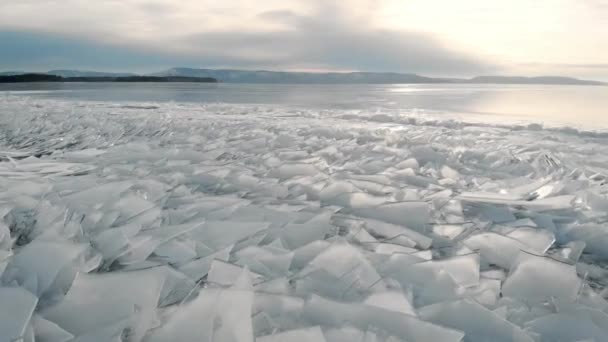 Północny krajobraz zamarzniętego jeziora lub rzeki. Odłamki lodu w pobliżu brzegu, w oddali góry i horyzont. — Wideo stockowe