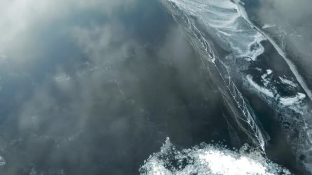 Es una vista aérea. El rápido movimiento de la cámara sobre el río recién congelado. El hielo es liso, con grietas y aire. Las nubes se reflejan en la superficie . — Vídeo de stock