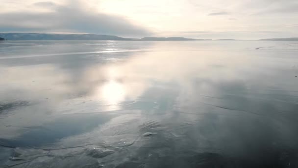 Είναι μια εναέρια άποψη. Το χειμερινό τοπίο του παγωμένου ποταμού. Ο πάγος αντανακλά τον ουρανό και τον ήλιο. Θερμοκρασία ψύχους. — Αρχείο Βίντεο