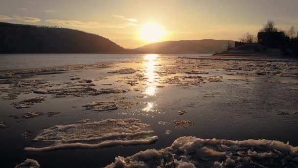 Its an aerial view. Sunset over the mountains. The river or lake is covered with people, freezes at the shore. Low flyover over water — Stock Video