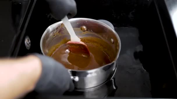 De koker koelt de pan af met het mengsel in het water. Er is een proces van het koken van peperkoek. — Stockvideo