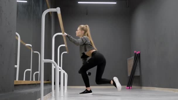 The girl in the sports room performs exercises. Squats with and without weight are well suited to maintaining a figure. A beautiful, fit body. — Stock Video